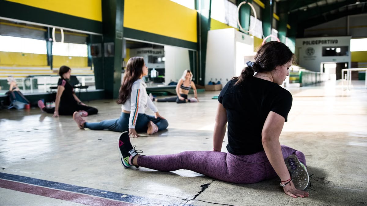 Women engaging in a group stretching session in an indoor gym.